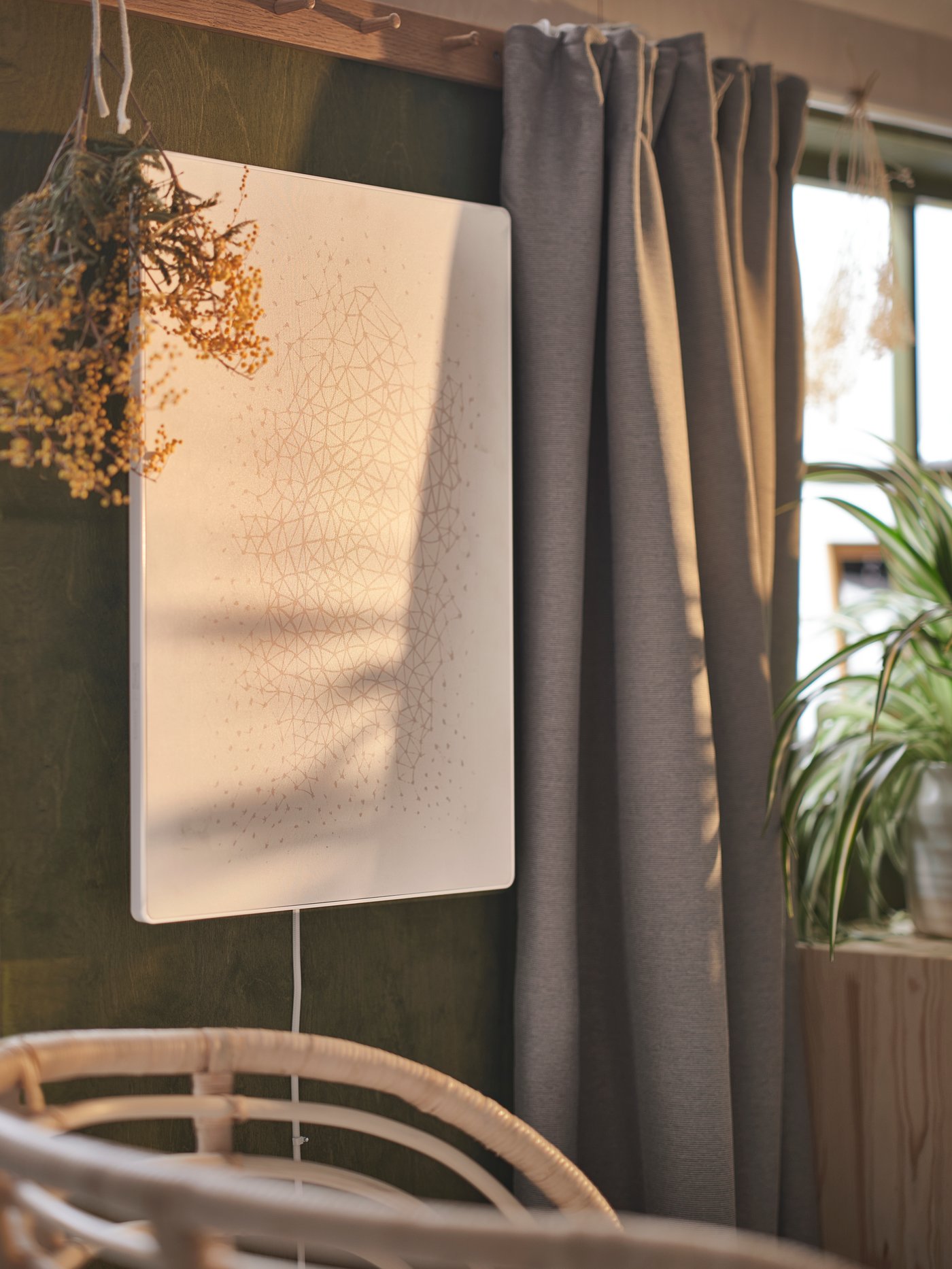 A white SYMFONISK picture frame with WiFi speaker on a green wall beside a window with grey VILBORG room darkening curtains.