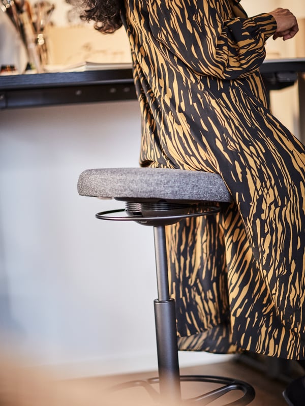 A woman sitting on a LIDKULLEN active sit/stand support.