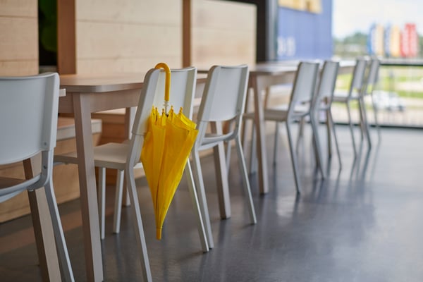Ein gelber Regenschirm hängt in einem IKEA Schwedenrestaurant an einem Stuhl.