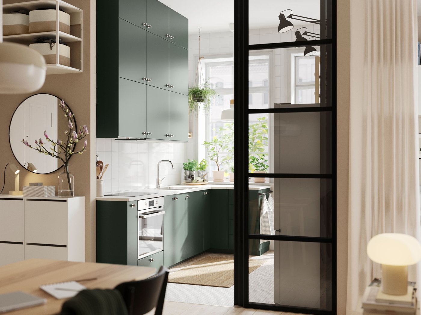 An open kitchen with deep green HAVSTORP kitchen fronts and wall cabinets up to the ceiling, next to a bright living room.