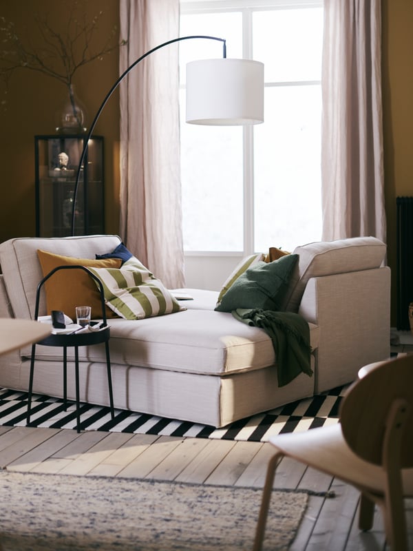 A living room with two beige KIVIK chaise longues with cushions by a window, both on a STOCKHOLM flatwoven rug.