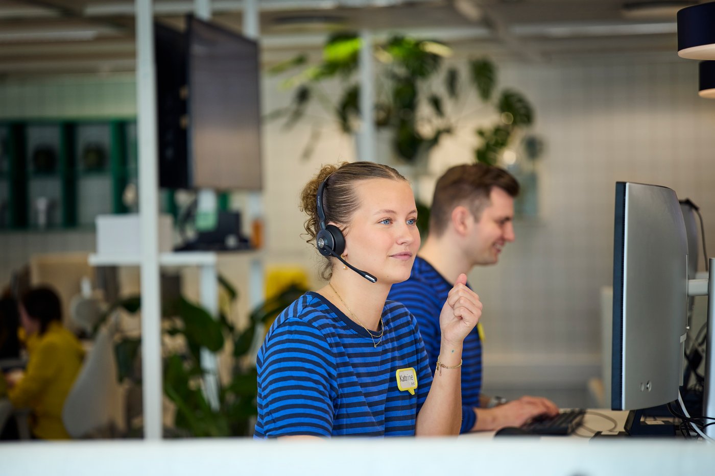 An IKEA coworker is sitting behind a computer with a headset
