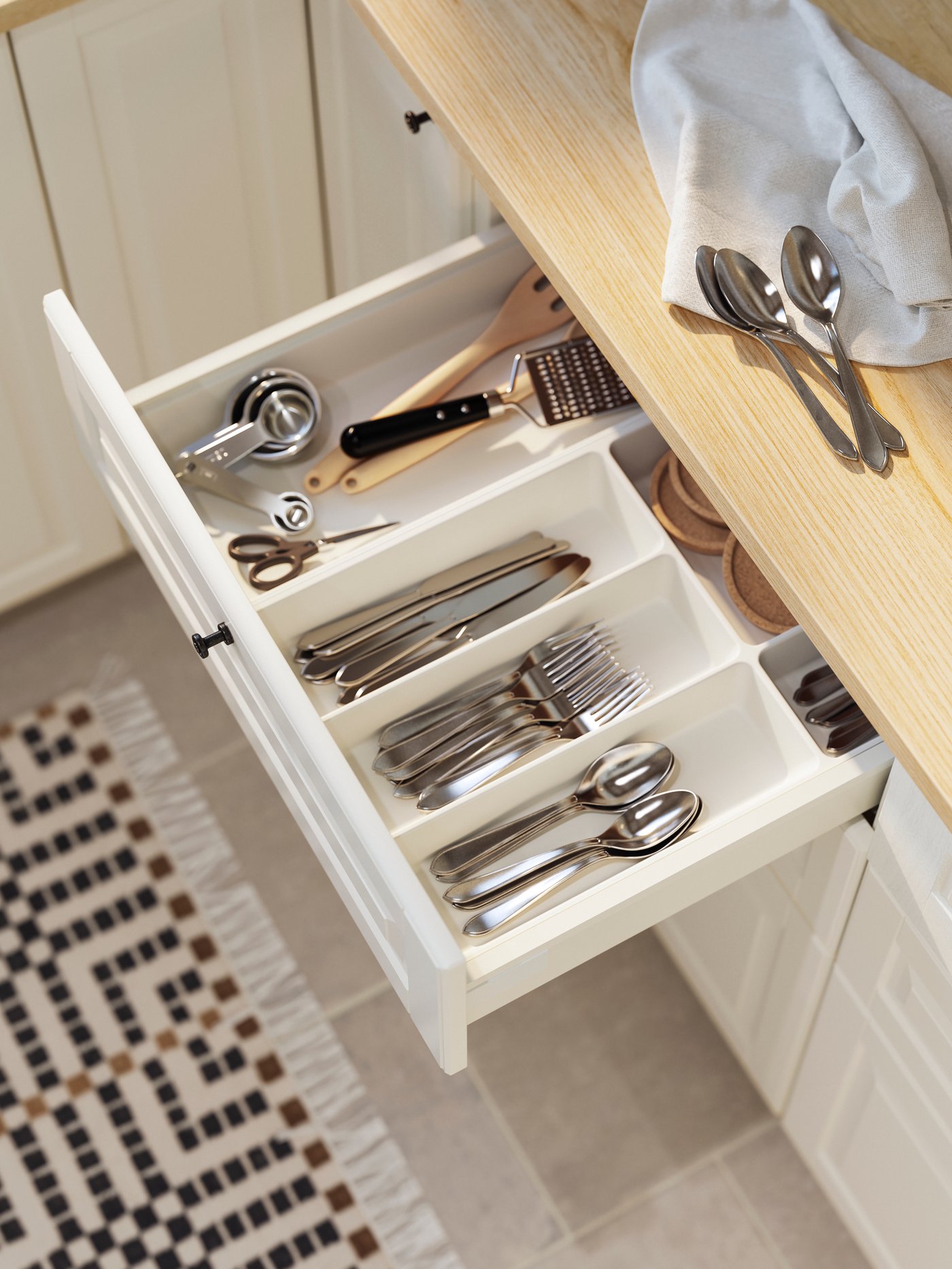 Un cajón de cocina abierto con cubiertos organiados en el interior.