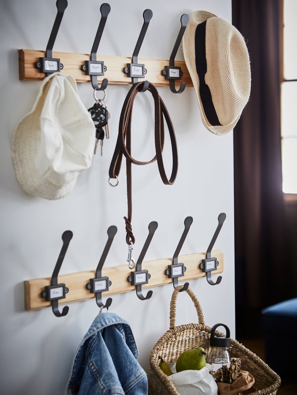 A jacket, a picnic basket, two hats, keys and a dog leash hanging on two pine/gray KARTOTEK racks with 5 hooks in a hallway.