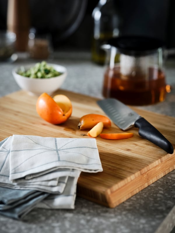 A terrazzo-style worktop with an APTITLIG butcher's block, on which lie a blue SANDVIVA tea towel and a black VÖRDA knife.