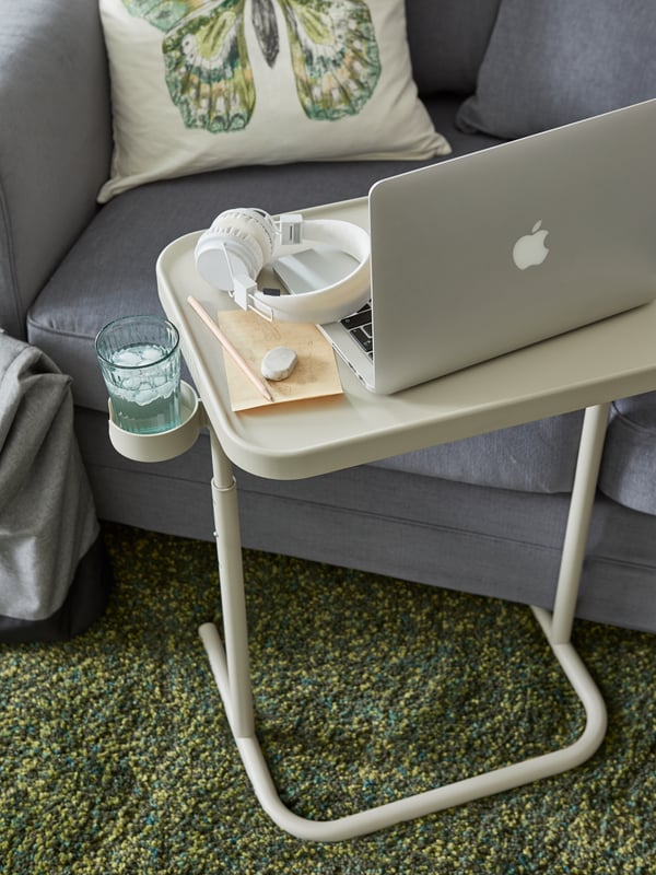 A laptop stand is placed by a sofa.