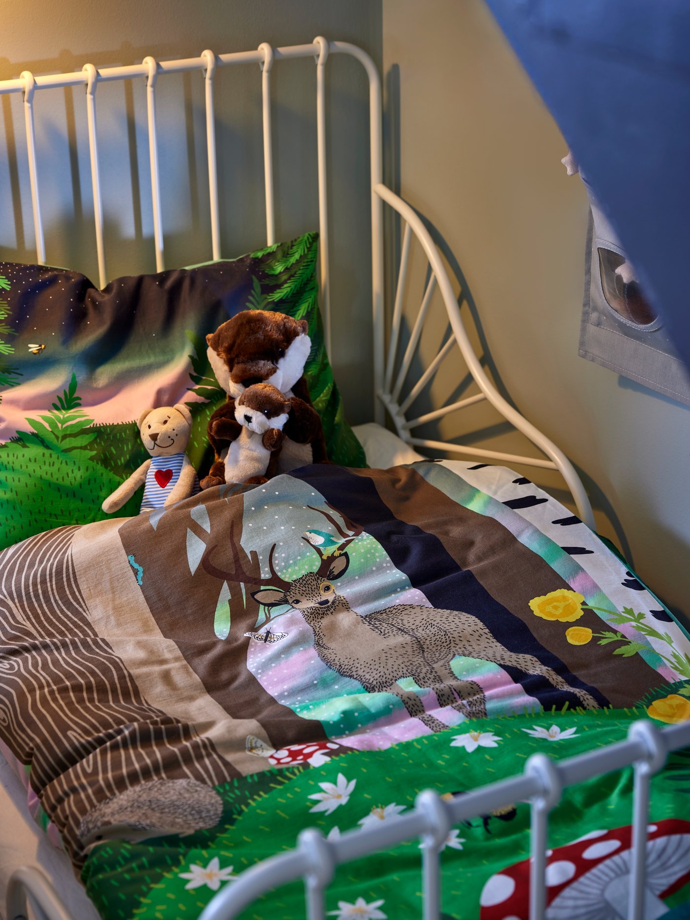 Close-up on soft toys sitting in MINNEN extendable children’s bed made up with SKOGSDUVA sheets.