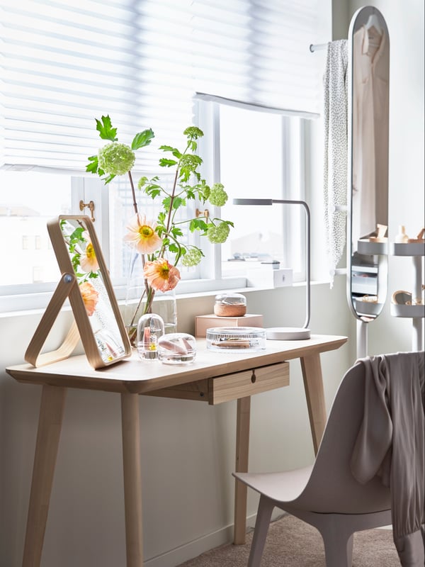 Sminkhörna med LISABO skrivbord framför ett fönster tillsammans med en IKORNNES bordsspegel. 
