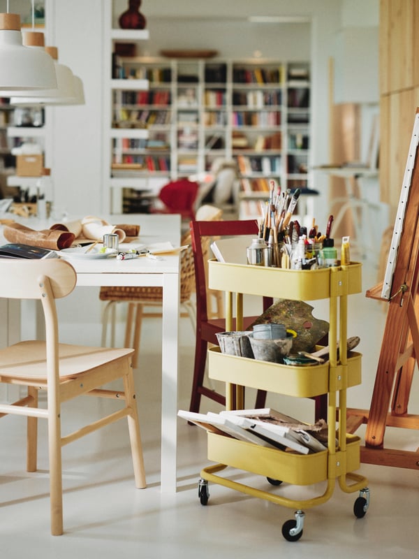 A MELLTORP table surrounded by RÖNNINGE and PINNTORP chairs and a yellow RÅSKOG serving cart in the foreground.