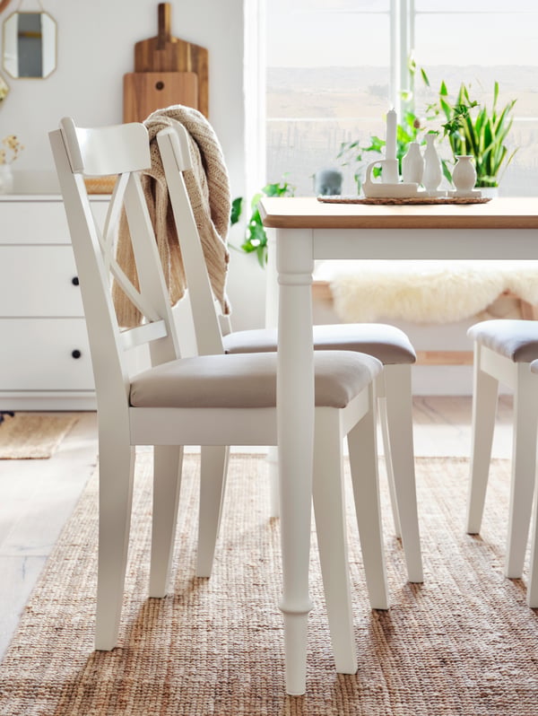 Silla blanca INGOLF con cojin junto a mesa blanca DANDERYD.
