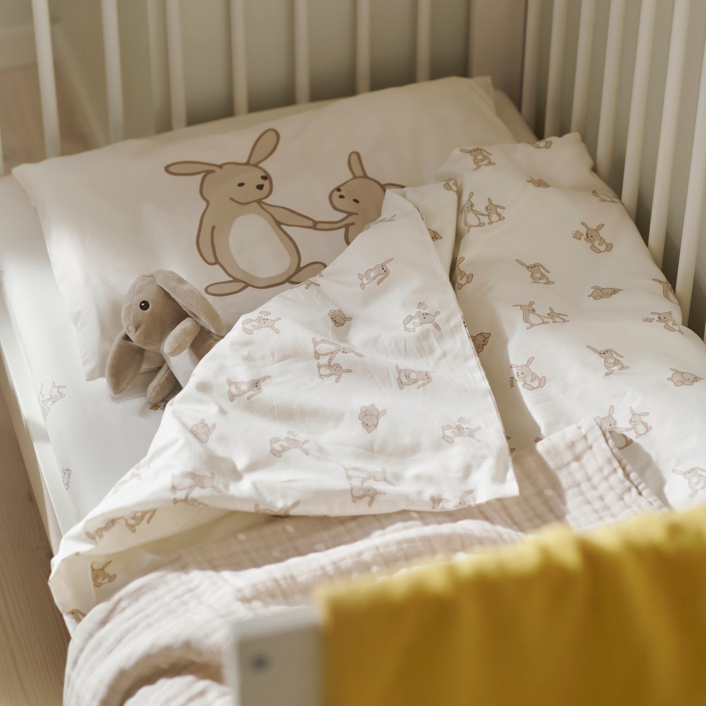 Copilot said:

Manta LEN blanca y beige con textura, colocada sobre una cuna junto a ropa de cama con estampado de conejos y una manta amarilla en una habitación infantil.