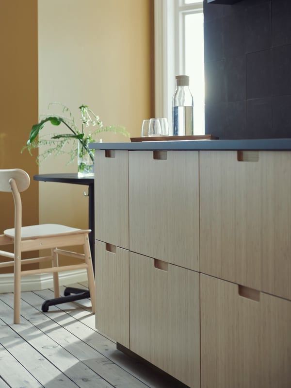 A section of a kitchen with SEKTION base cabinets with bamboo fronts, beneath an anthracite EKBACKEN countertop.