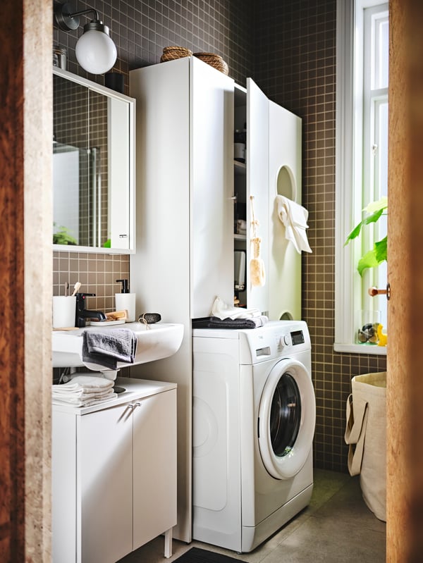 A space holds a NYSJÖN bathroom furniture set, white units for laundry sorting and a STORAVAN soap dispenser.