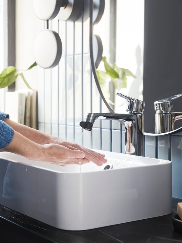 A person is washing their hands at a bathroom sink.