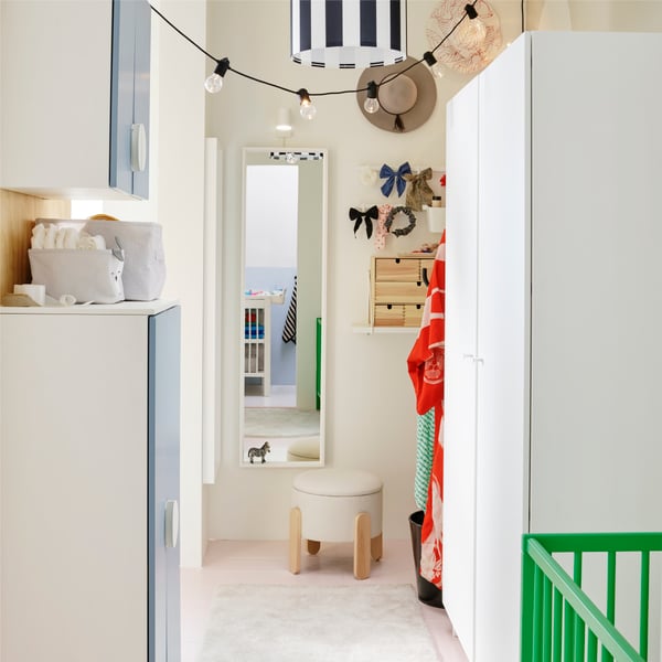 A dressing area with a white PLATSA wardrobe on one side and a NISSEDAL mirror on the wall at one end with a stool in front.