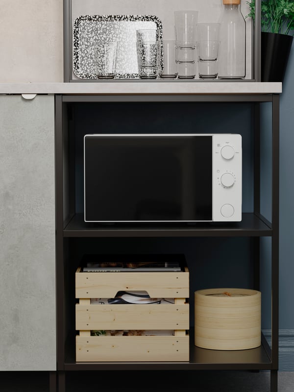 A TILLREDA microwave oven in white on an ENHET base frame with shelves in anthracite, with various boxes and glasses.