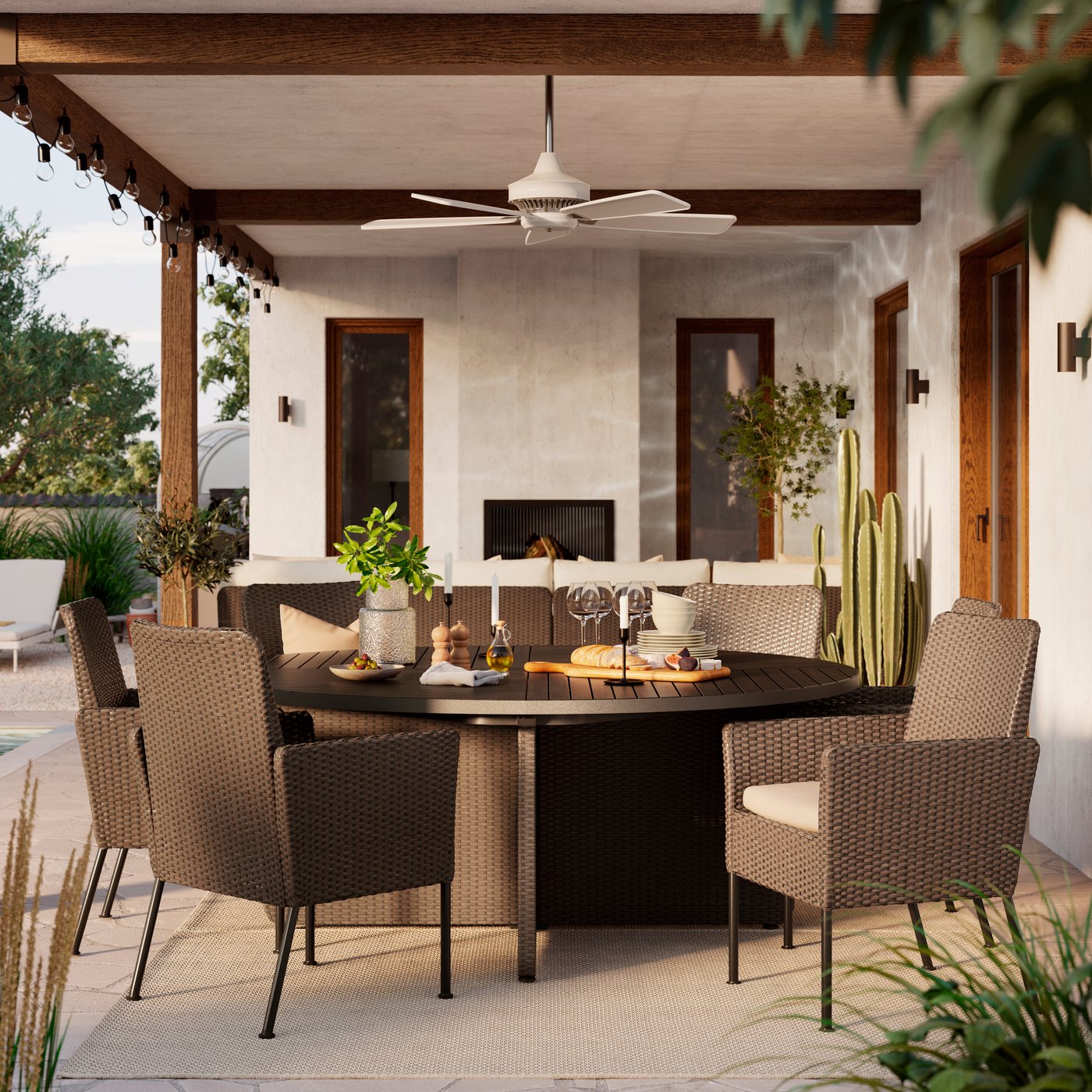 A large outdoor space with dark grey VITTSKÄR table and eight rattan dining chairs under a roof. Sun is shining.