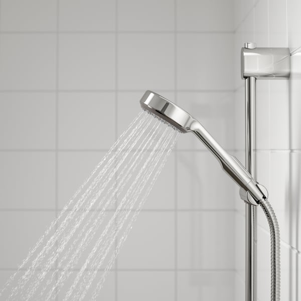 Water-efficient shower head in use in a tiled bathroom.				