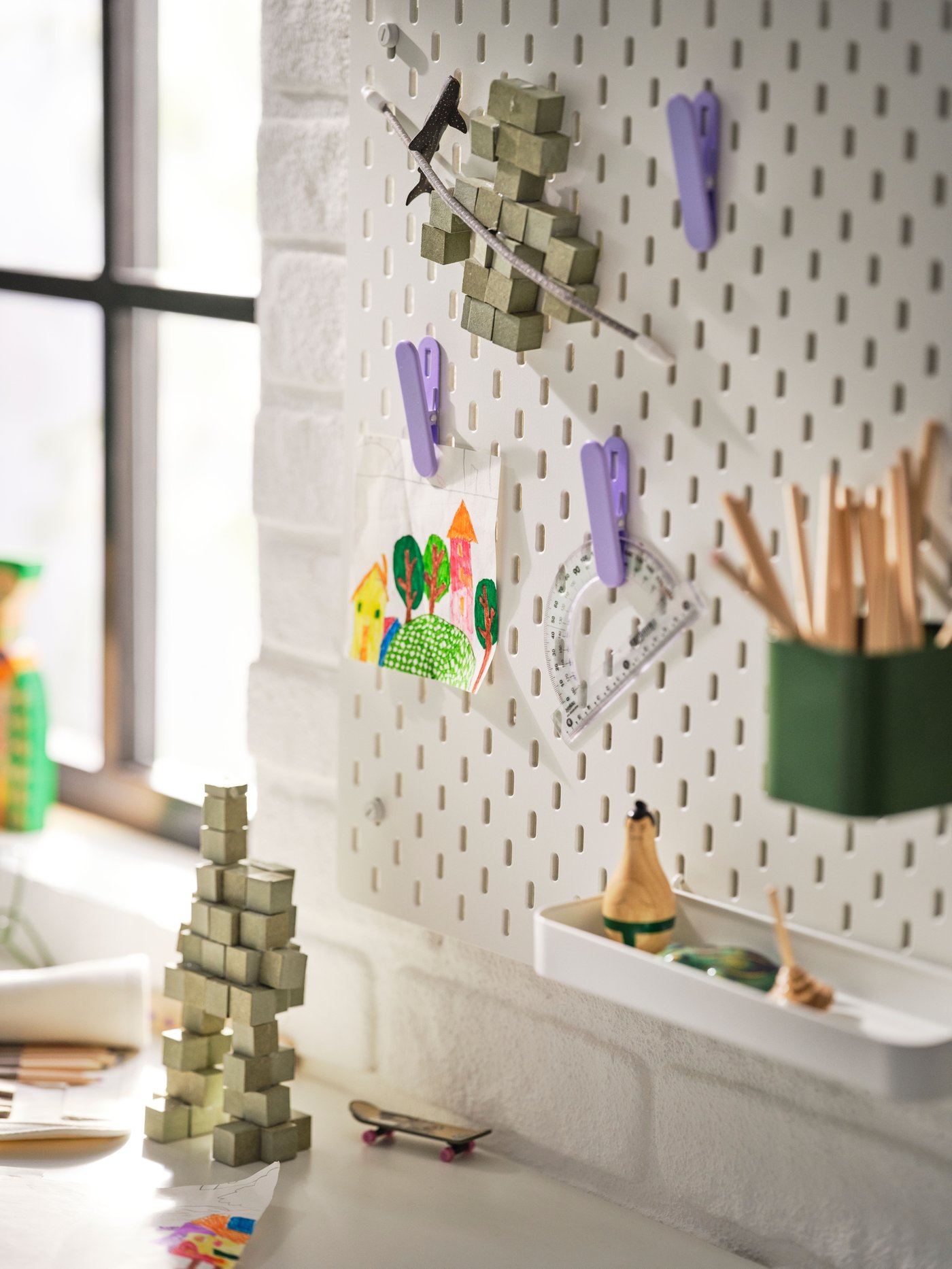 A white SKÅDIS pegboard in the childrens room