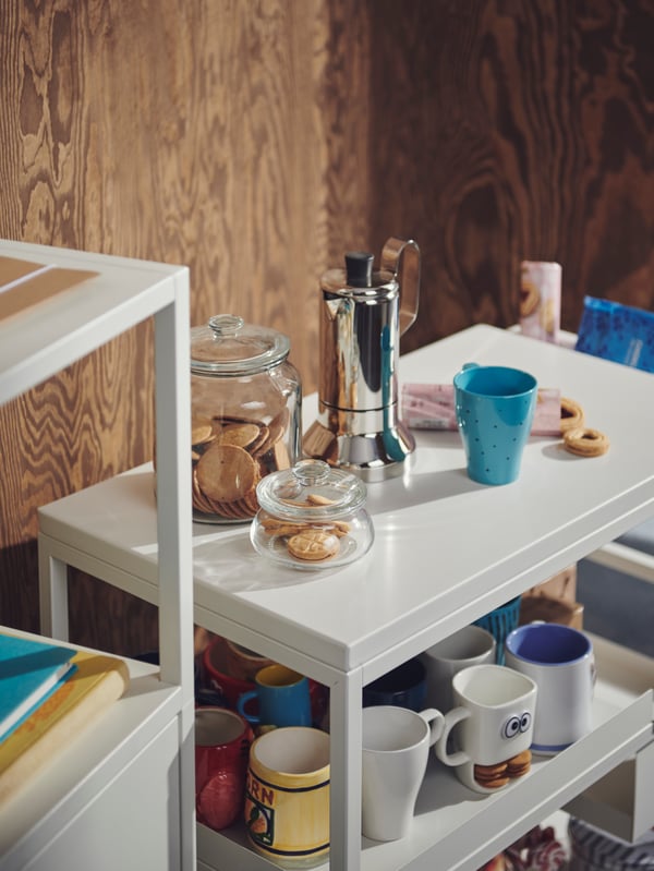 Cookies in VARDAGEN glass jars amid other coffee-break accessories and personalised mugs on a TROTTEN trolley.