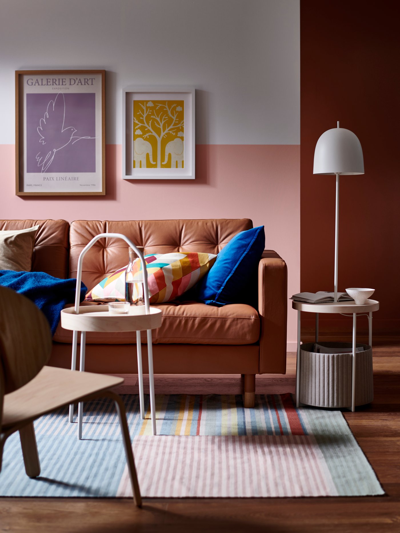A BURVIK side table stands in front of a LANDSKRONA sofa which has a blue KLIPPOXEL throw and extra cushions on it.