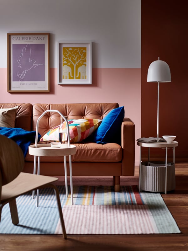 Ein BURVIK-Beistelltisch steht vor einem LANDSKRONA-Sofa, auf dem eine blaue KLIPPOXEL-Decke und zusätzliche Kissen liegen.