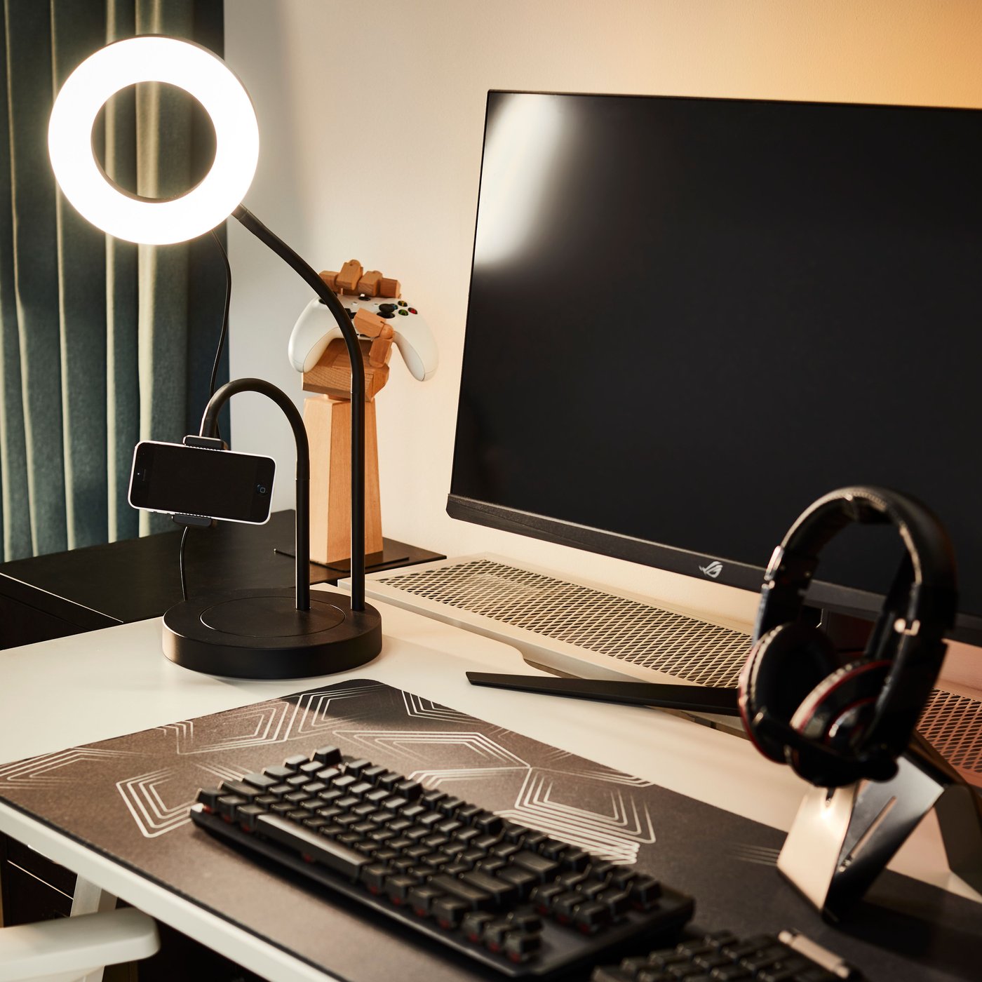 Anneau lumineux LÅNESPELARE avec support pour téléphone sur un bureau, près d’un écran et d’un clavier. Un casque audio est en place sur son support.