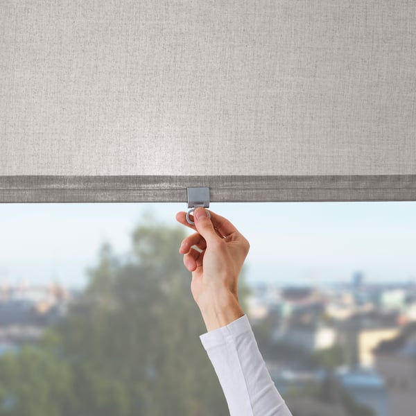 Hand adjusting an insulating window blind to help regulate indoor temperature.				