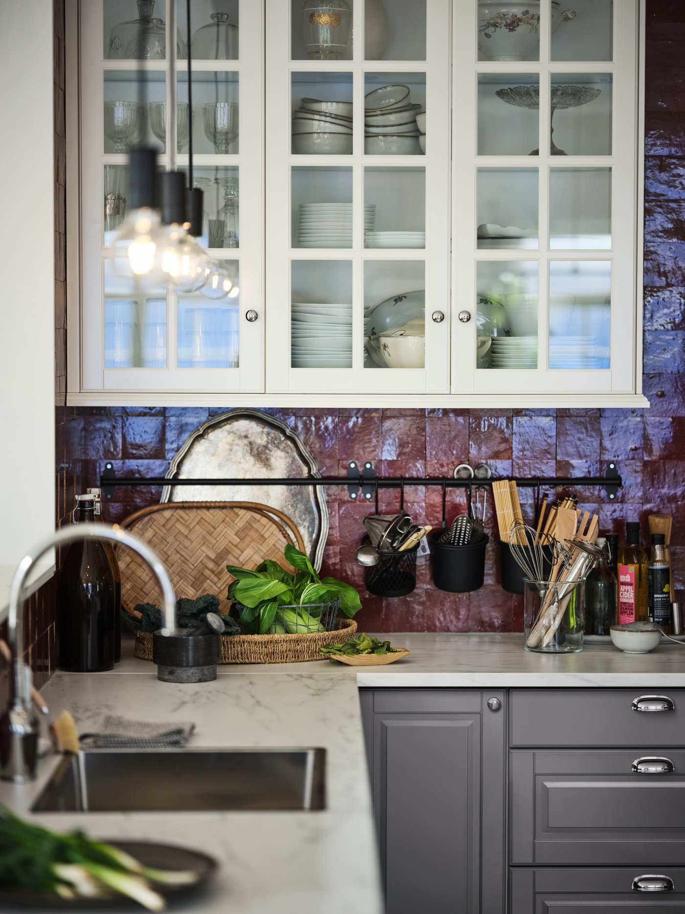 A SEKTION/MAXIMERA kitchen with a white marble effect/laminate EKBACKEN worktop and a white glass-door wall cabinet.