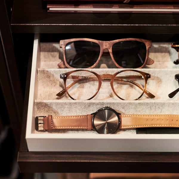 A light grey KOMPLEMENT insert in a open drawer that has sunglasses and a watch in the compartments.