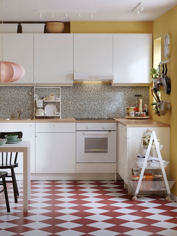 Dapur yang bersifat eklektik dengan lantai bercorak dam berwarna merah dan putih, dinding berwarna kuning dan kabinet dasar dan dinding KNOXHULT berwarna putih.