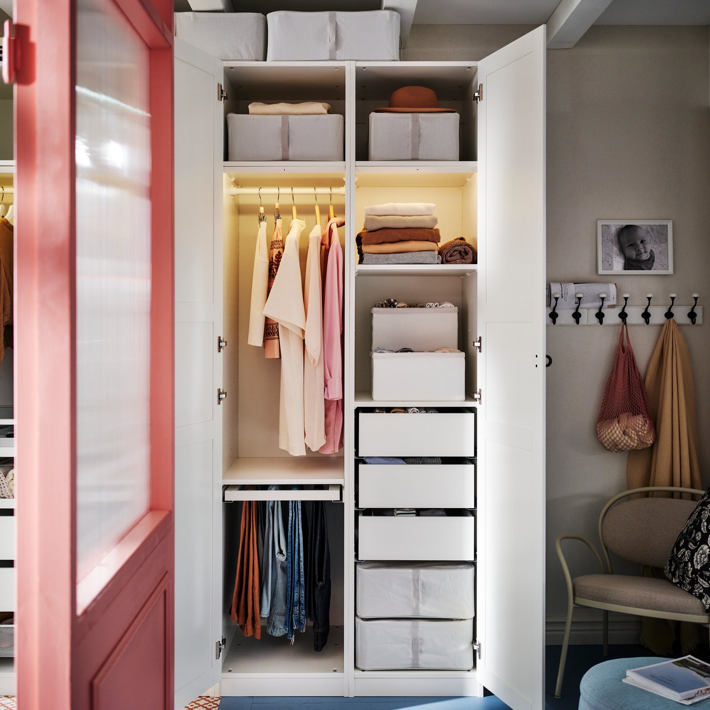 A white PAX/TYSSEDAL wardrobe with the doors open showing organised clothes and two HEMMAFIXARE boxes on the top shelves.