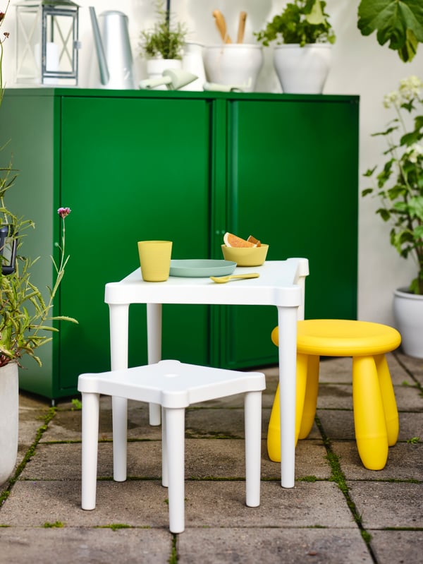 MAMMUT and UTTER children table and chiar in an outdoor area in front of a green SUNDSO cabinet. 