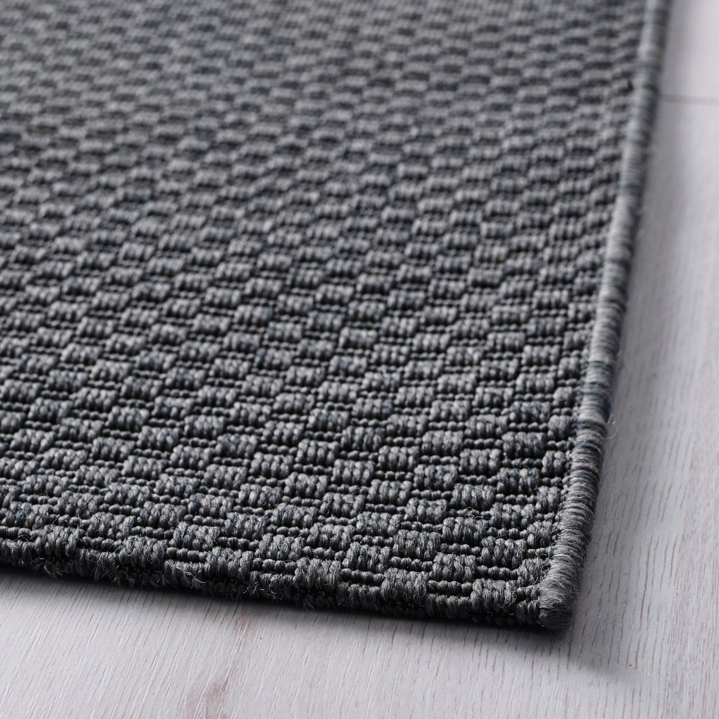 Una alfombra MORUM de tejido plano color gris oscuro, para interior y exterior.