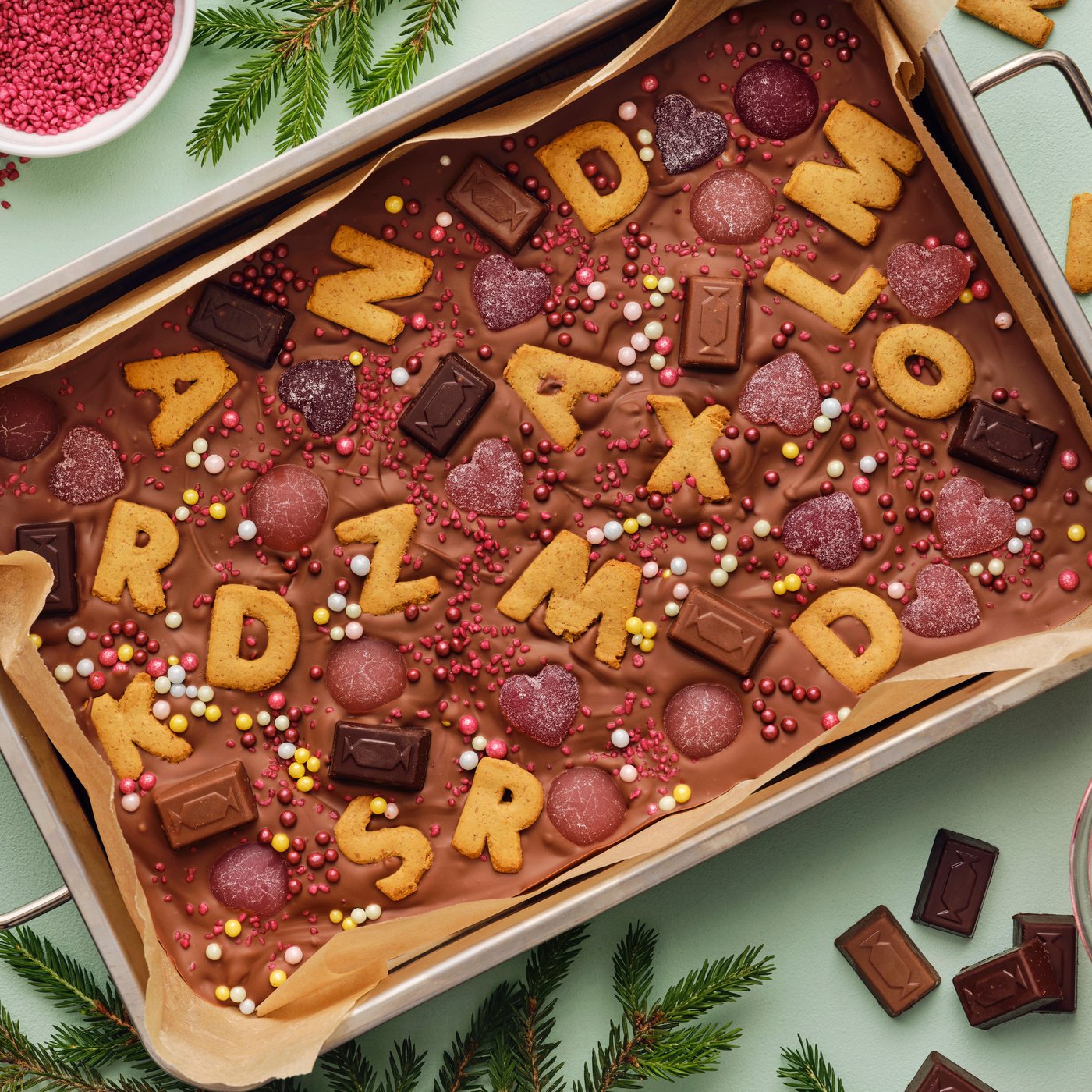 A tray with melted chocolate, colourful sweets, and KAFFEREP letter-shaped biscuits, in a fun and festive dessert.