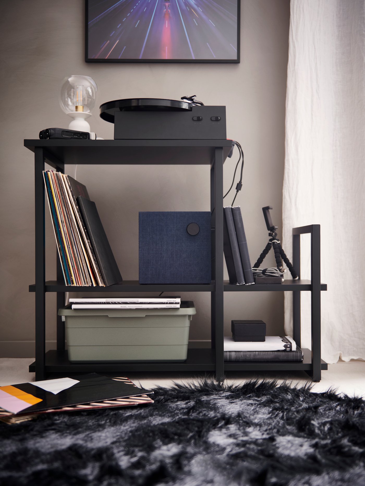 A lit black OBEGRÄNSAD LED work lamp on a black desk next to an open laptop with keyboards in the background.