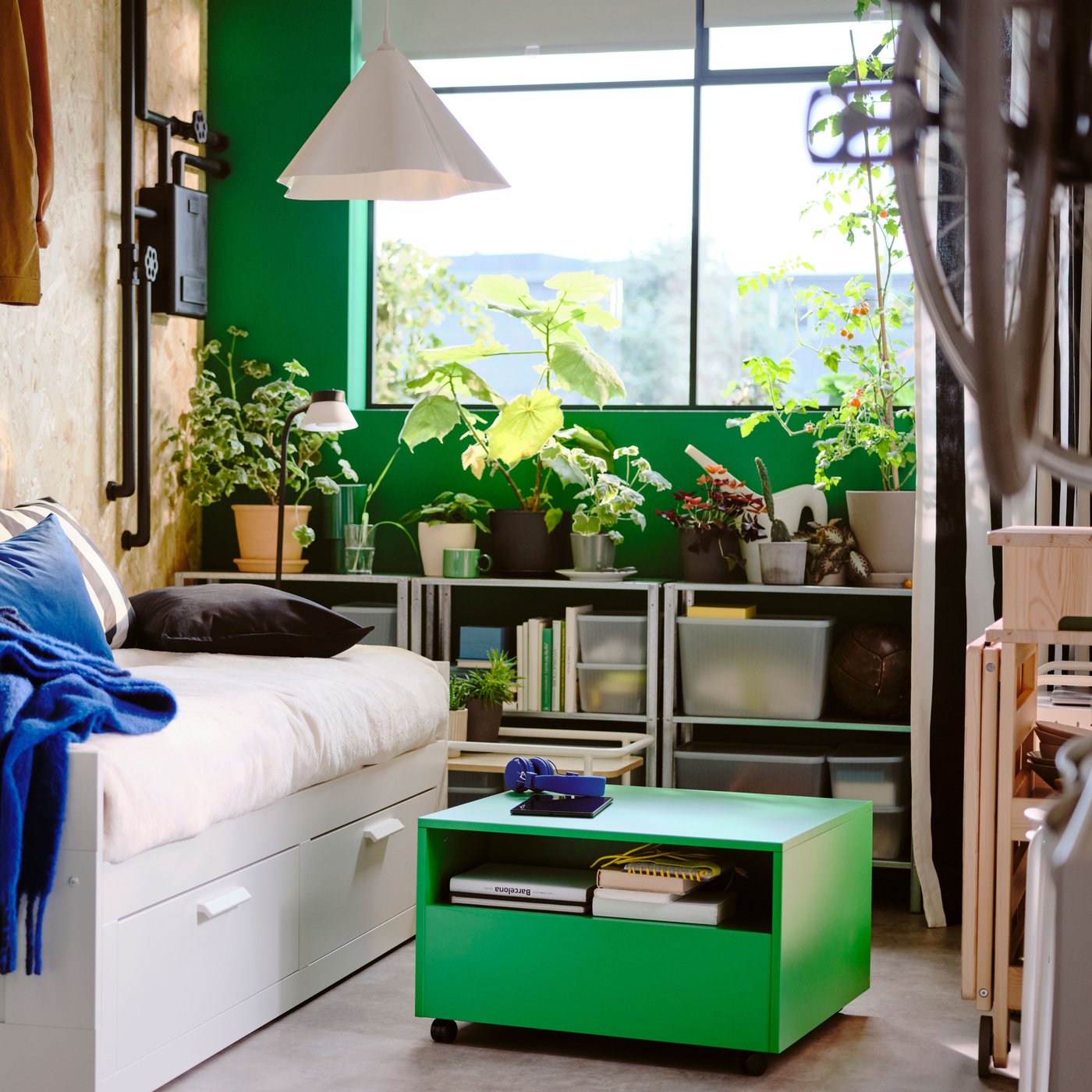 A white BRIMNES day-bed with 2 drawers in a green and white bedroom with a green GARNANÄS coffee table on the floor in front.