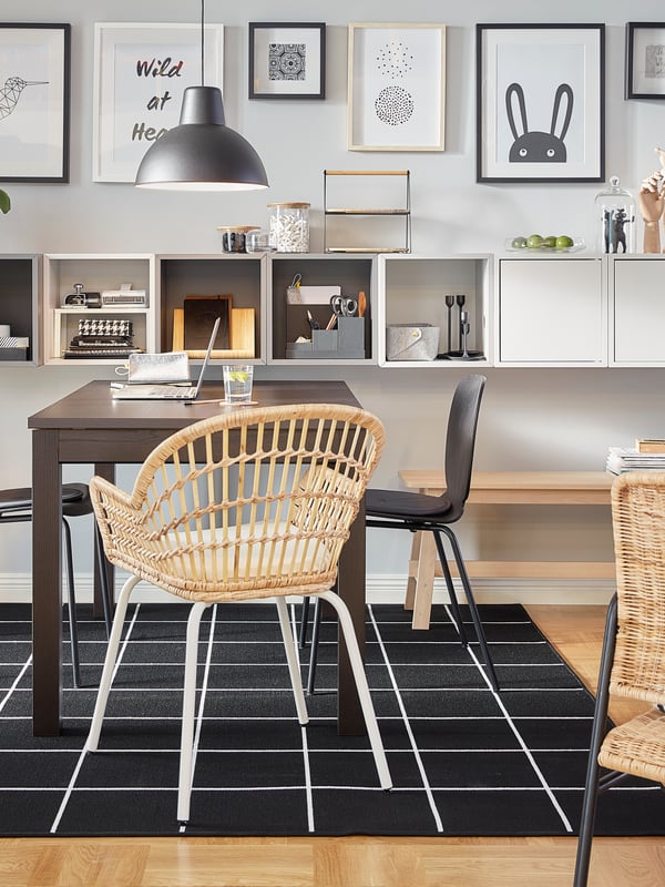 An EKET combination with both open and closed cabinets in grey and white is wall-mounted by a brown table.