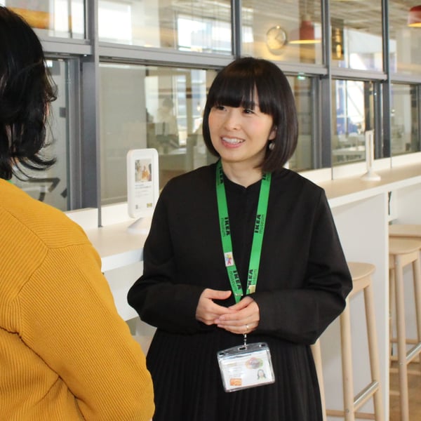 イケアレストランのカウンター前で、緑のストラップを付けたコワーカーが来店客と向かい合って立っている