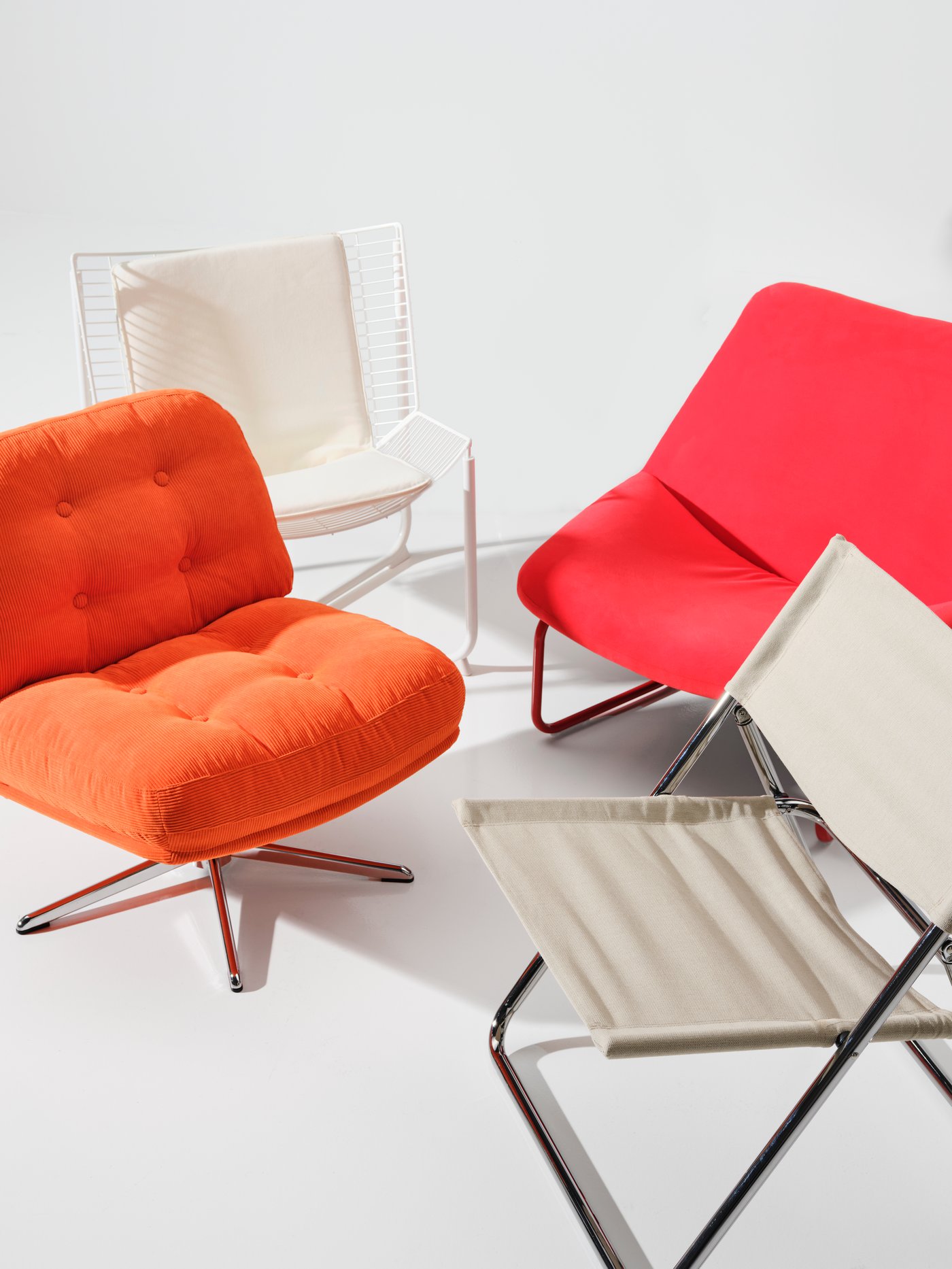 Four different chairs from the Nytillverkad collection are placed in a white room. Among them is a DYVLINGE swivel armchair.