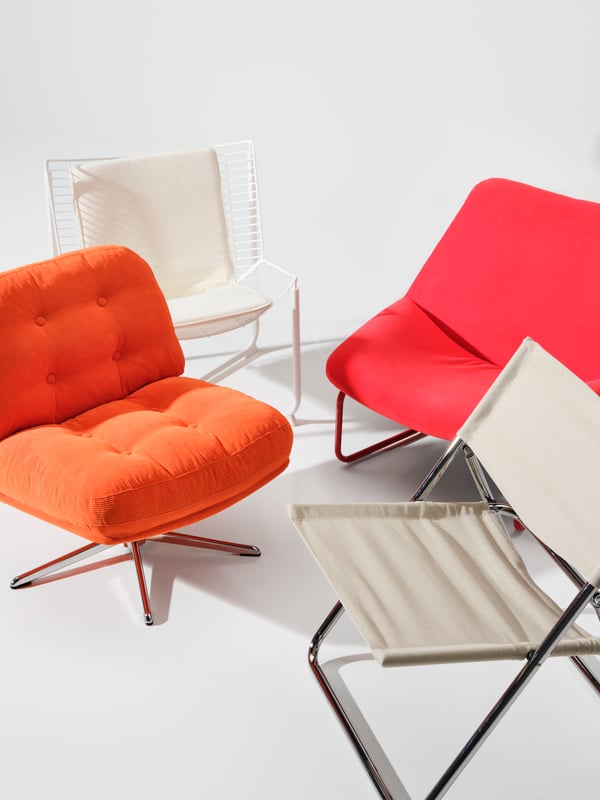 Four different chairs from the Nytillverkad collection are placed in a white room. Among them is a DYVLINGE swivel armchair.