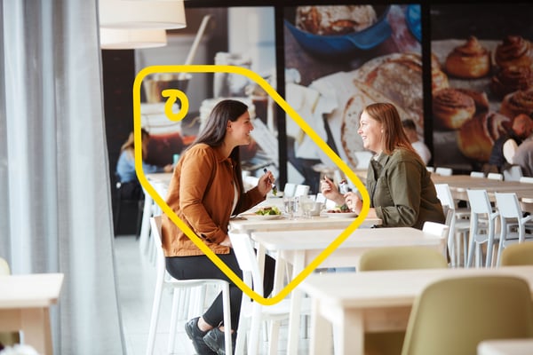 Dve osobe u IKEA Švedskom restoranu sede jedna nasuprot druge i jedu.