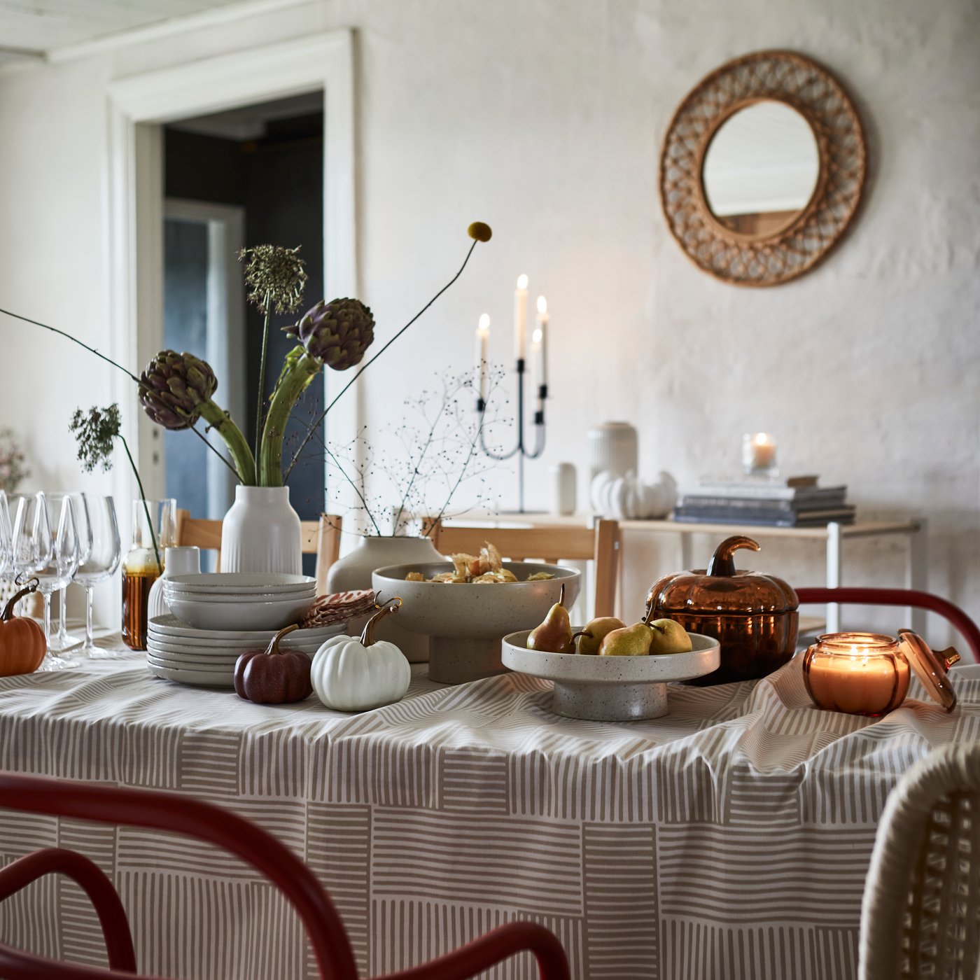 A light beige HÖSTAGILLE serving stand and bowl showcase fruit on a beautifully set dining table.