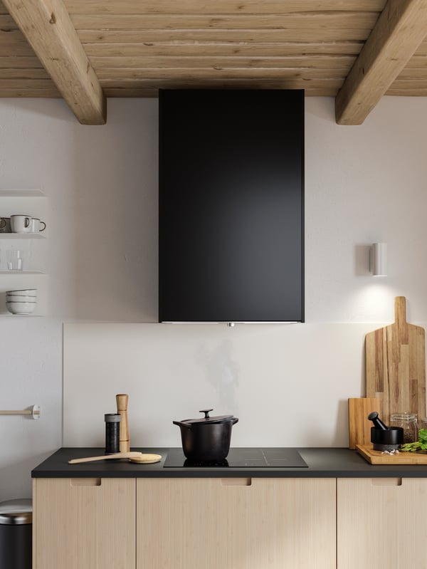 A built-in extractor hood with an anthracite door, a matte anthracite worktop and light bamboo drawer fronts.