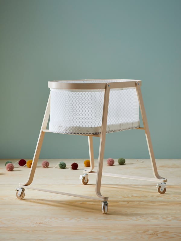 Un berceau ÄLSKVÄRD avec matelas en bouleau dans une pièce au sol en bois et aux murs gris/vert.