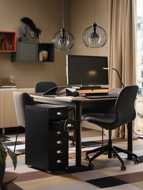 A STRANDTORP extendable table set up for work with a monitor on a stand and a lamp on top, and an office chair in front.