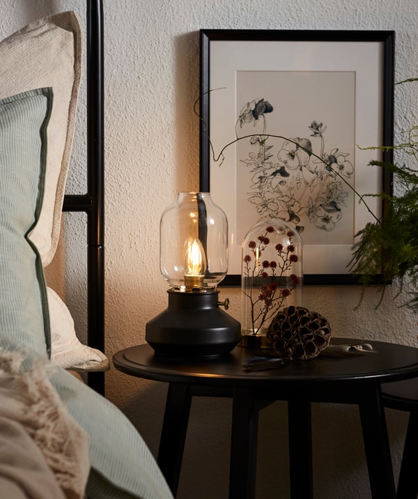 A TÄRNABY table lamp on a KRAGSTA bedside table next to a bedframe.