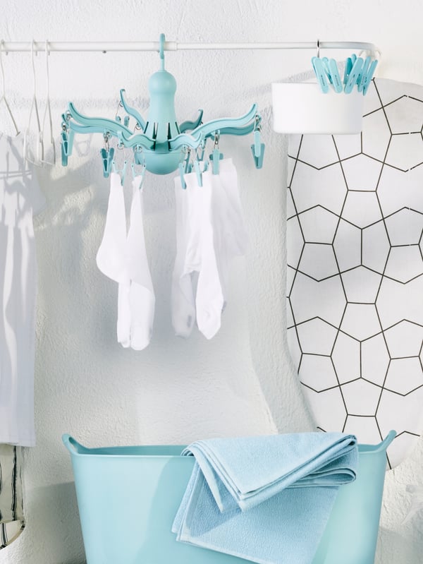 Colgador de ropa celeste PRESSA con medias blancas colgando sobre un bolso celeste TORKIS.