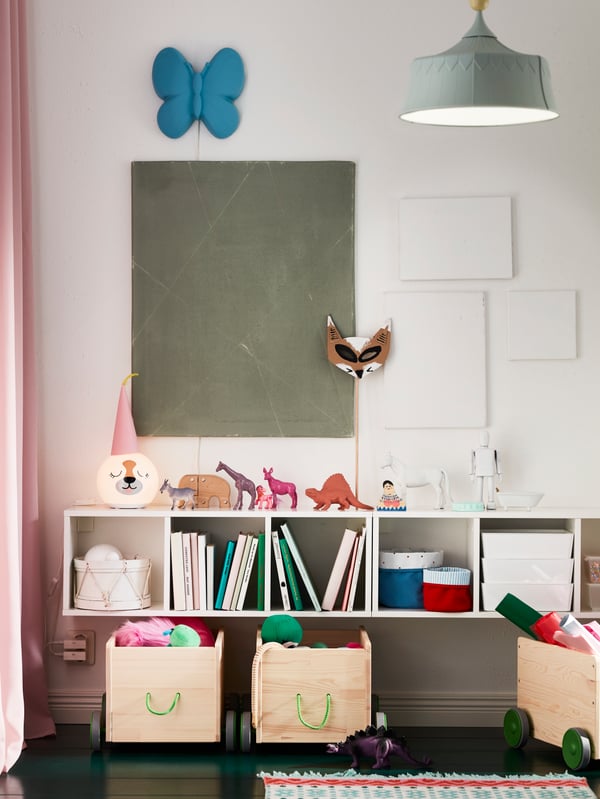 In a child’s room, FLISAT toy storage with wheels sit under SMÅGÖRA shelf units which store books, toys and boxes.