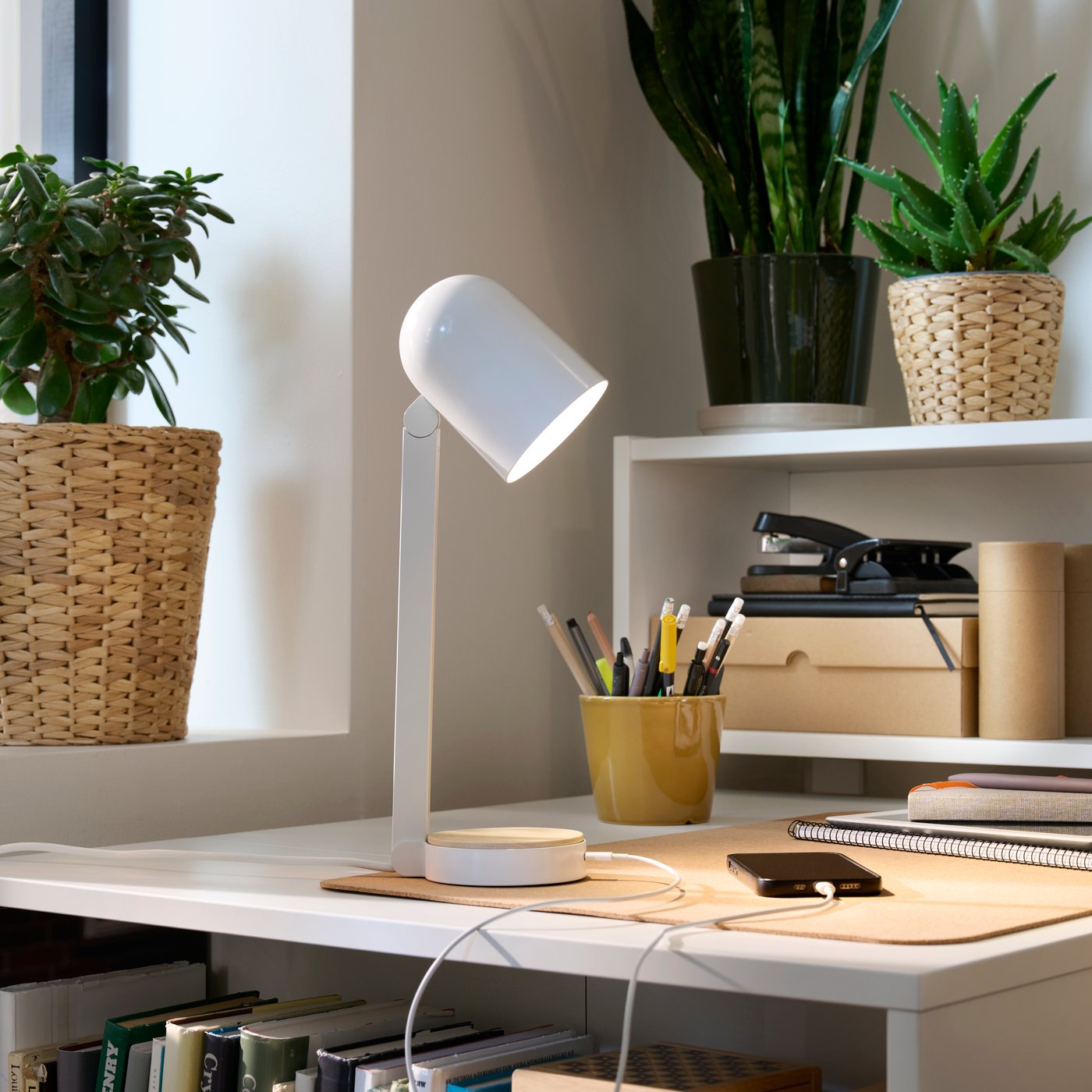Un coin d'une chambre pièce avec un bureau blanc BILLY rempli d'accessoires de bureau et éclairé par une lampe de bureau blanche ENSMÄRKE lampe .